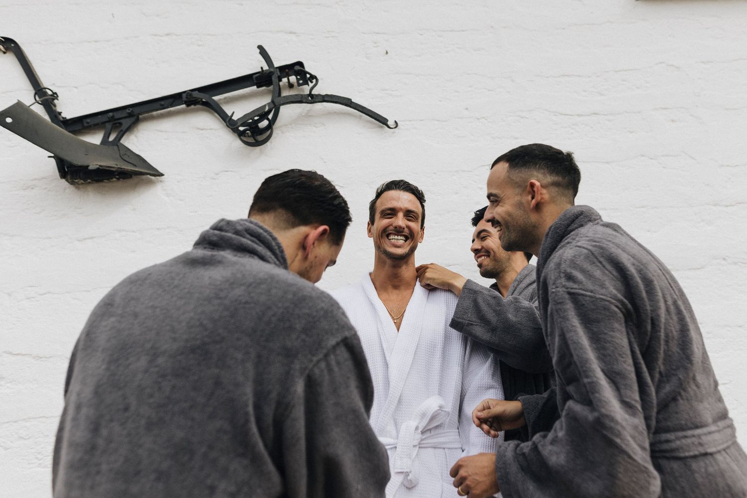 A group of people sharing joyful moments and laughter against a white wall background.