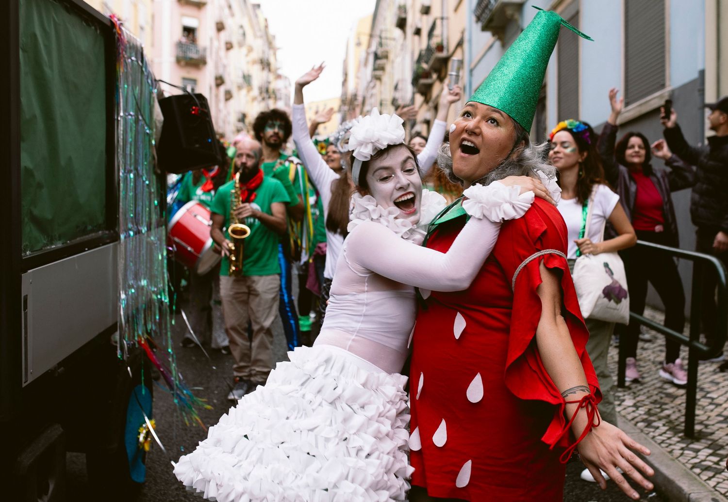 Festive revelers in colorful costumes celebrate during carnival on a crowded city street.