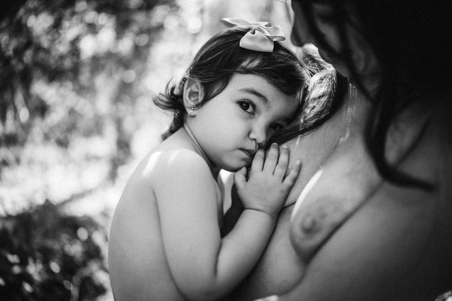 Black and white intimate breastfeeding portrait showing tender skin-to-skin bonding moment.