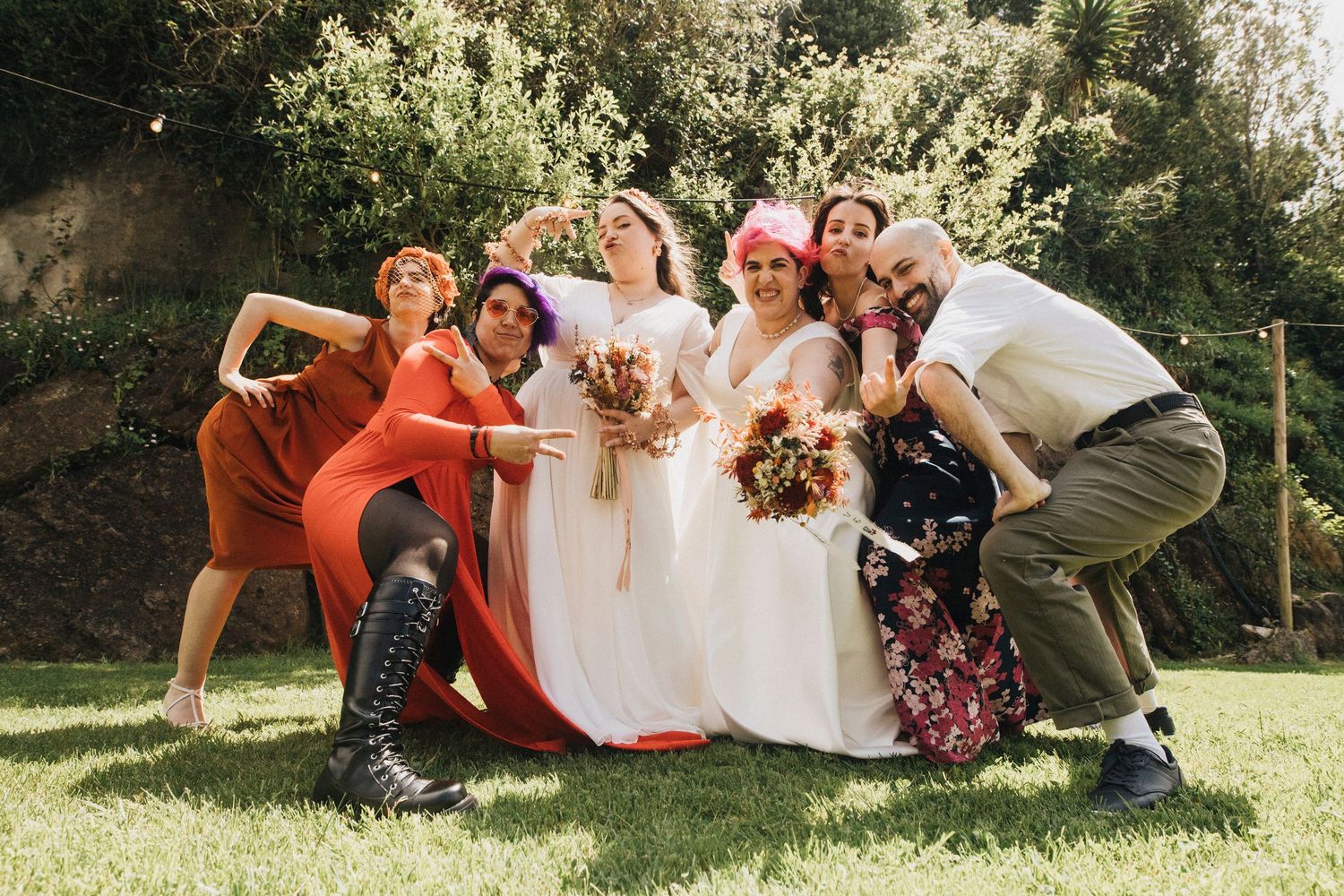Wedding party lounges casually on grass during outdoor photo session.