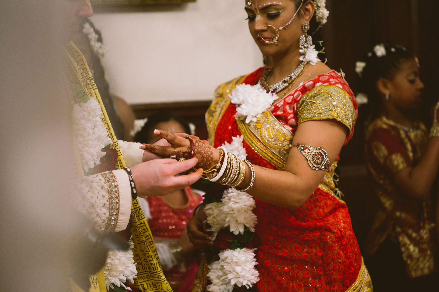 Close-up view of Indian wedding ceremony showing detailed traditional outfits and white floral decorations.