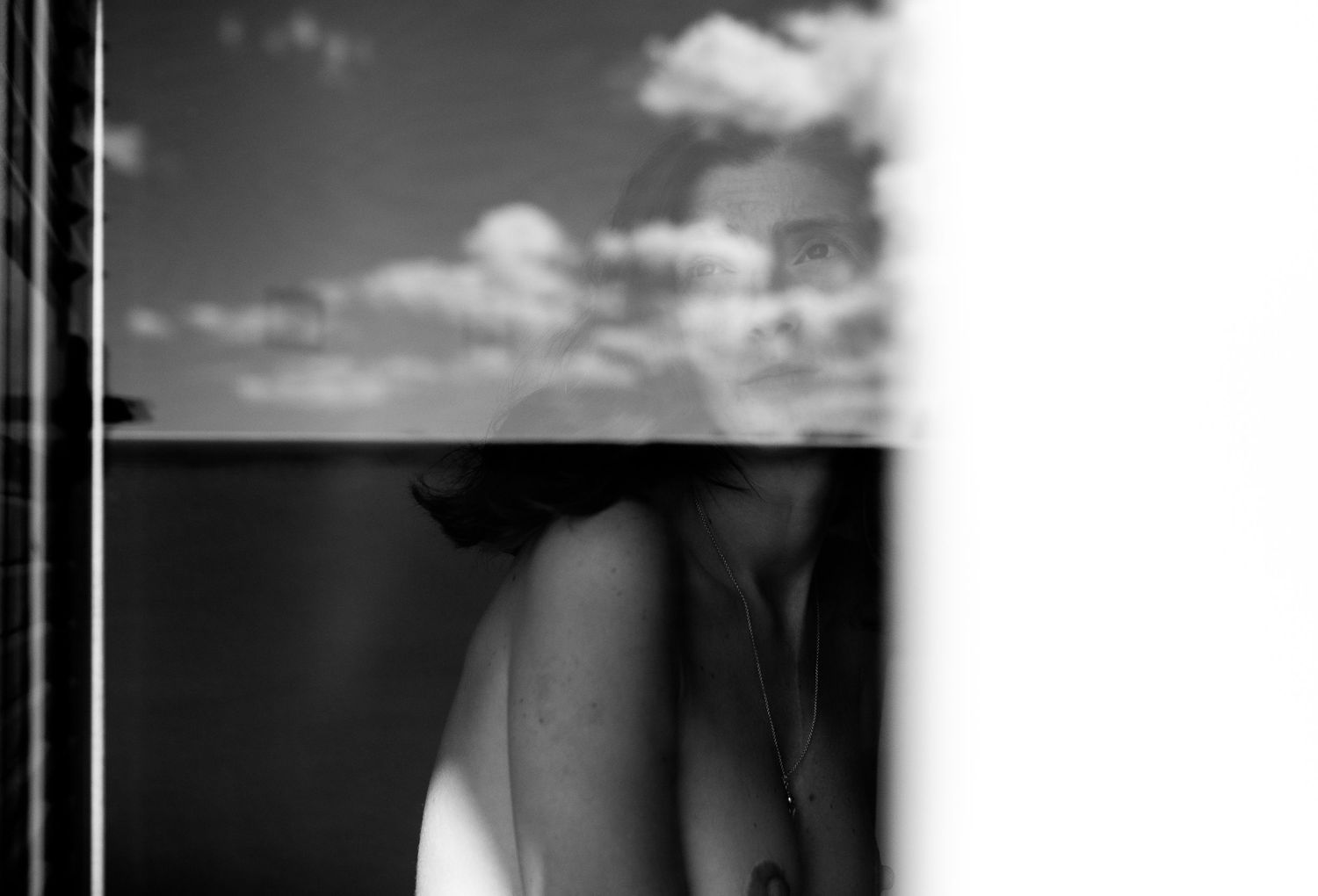 A black and white artistic photograph showing a silhouetted figure against a cloudy sky background.