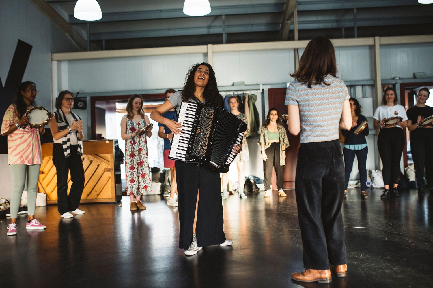 Dance students practicing choreography in a bright studio space with overhead lighting.