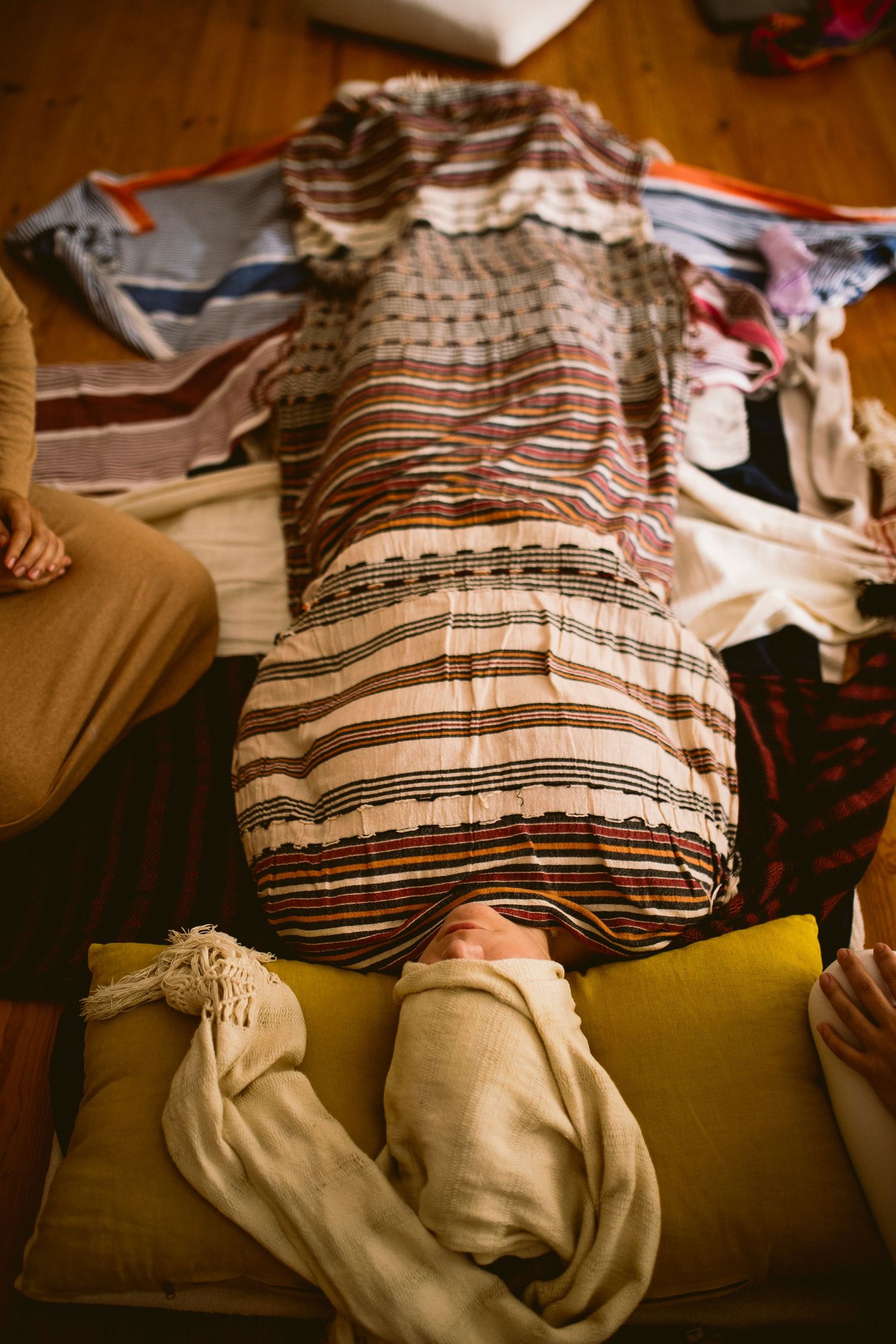 Person lying down on a couch with striped clothing in a dimly lit room.