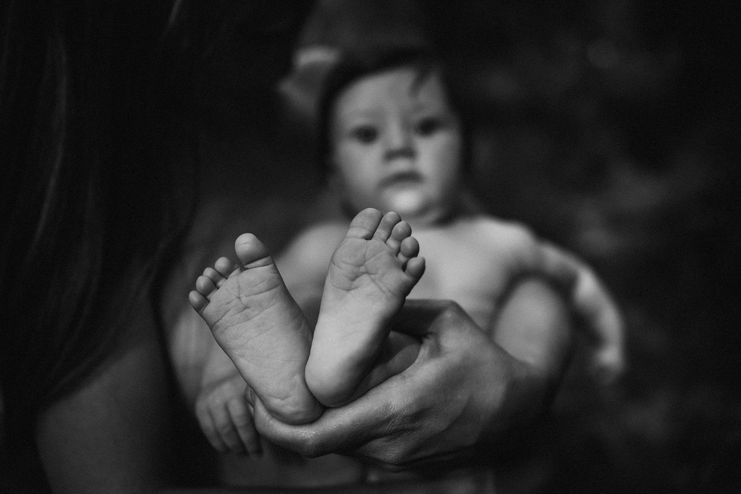 Artistic black and white detail shot of infant feet being held.