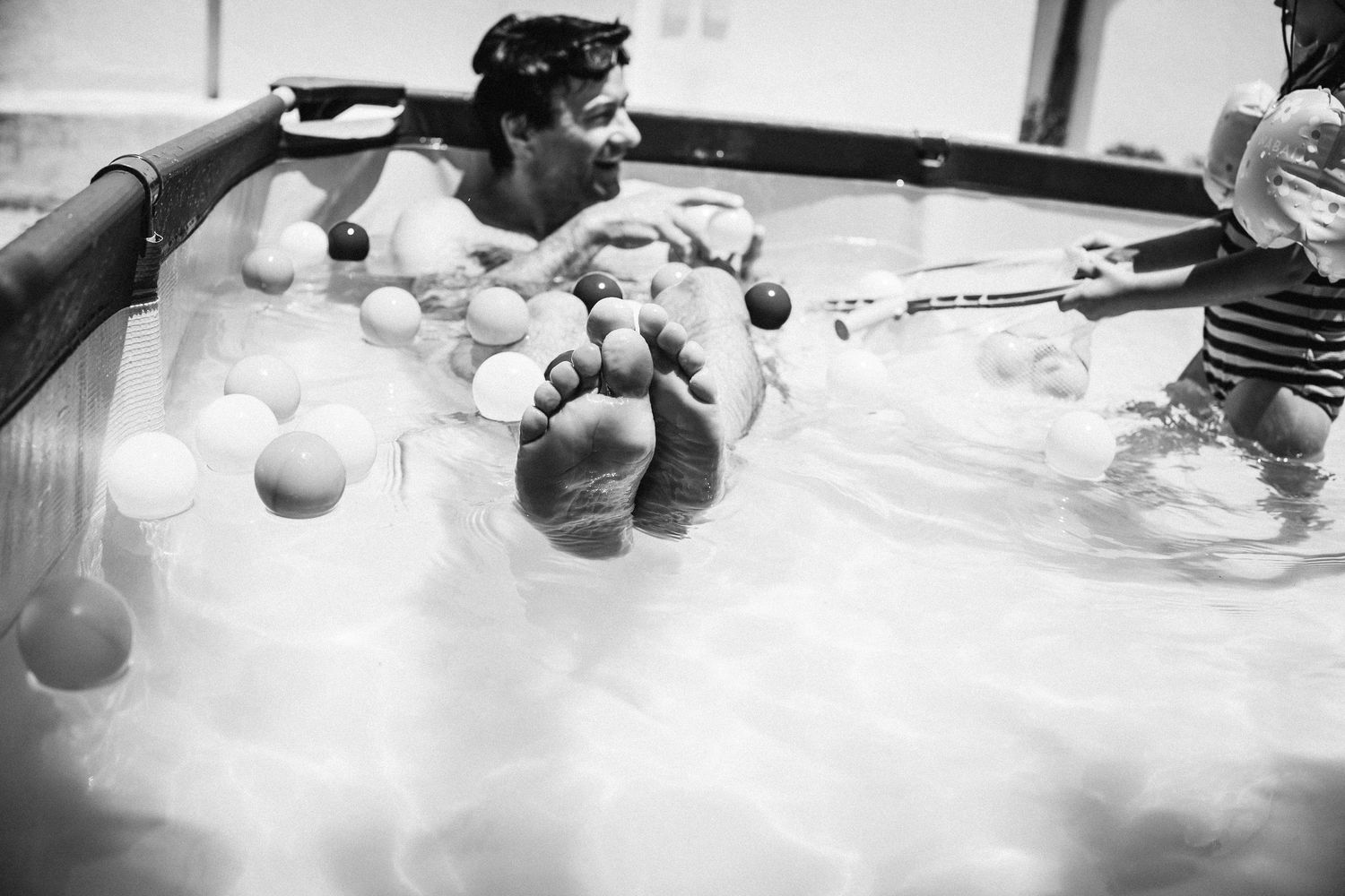 Black and white photo sequence showing a pool cue striking a cue ball into other billiard balls on a table.