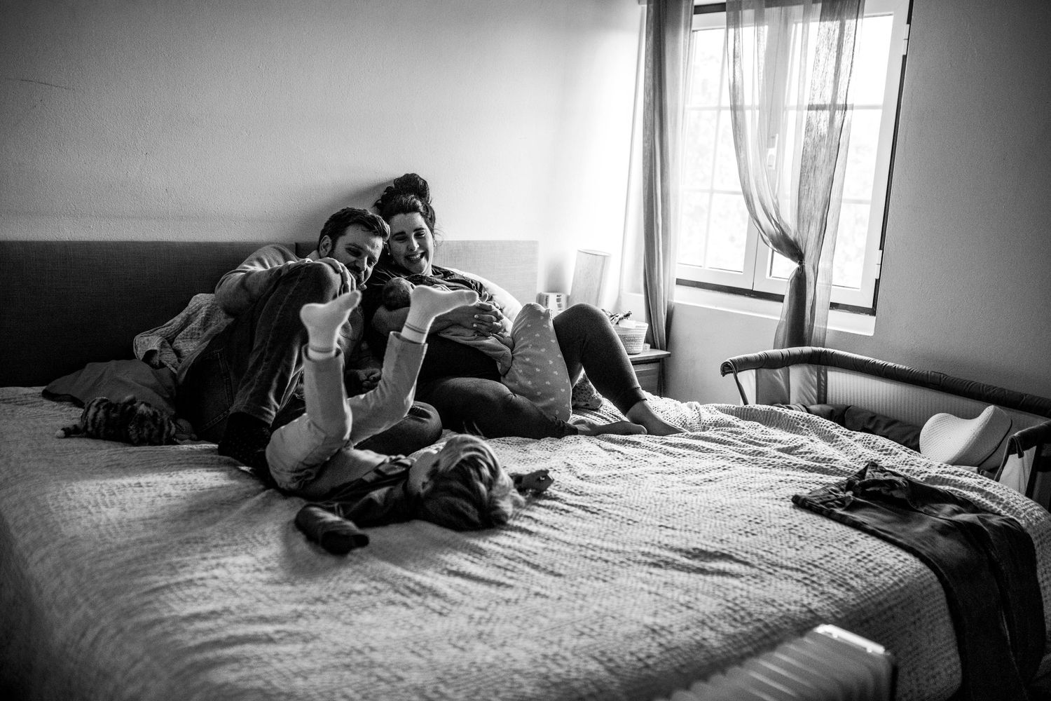 Black and white panoramic series of intimate family moments on bed.
