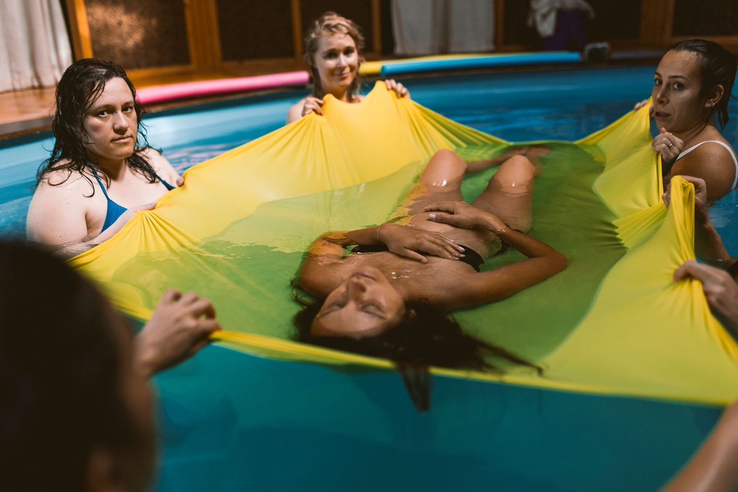 Children play with a yellow parachute during an outdoor activity session.