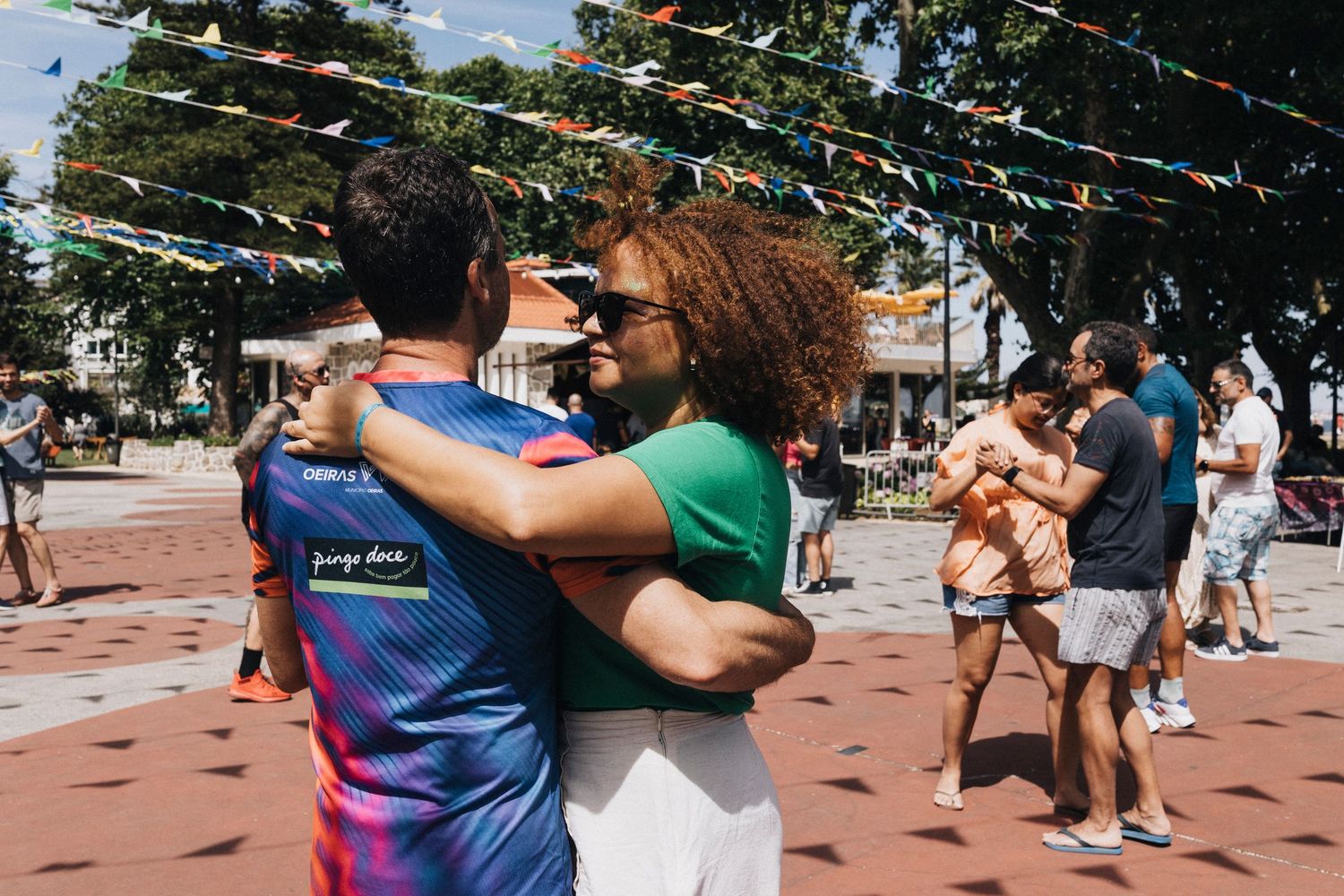 Couples dance together in an outdoor plaza during a sunny afternoon dance gathering.