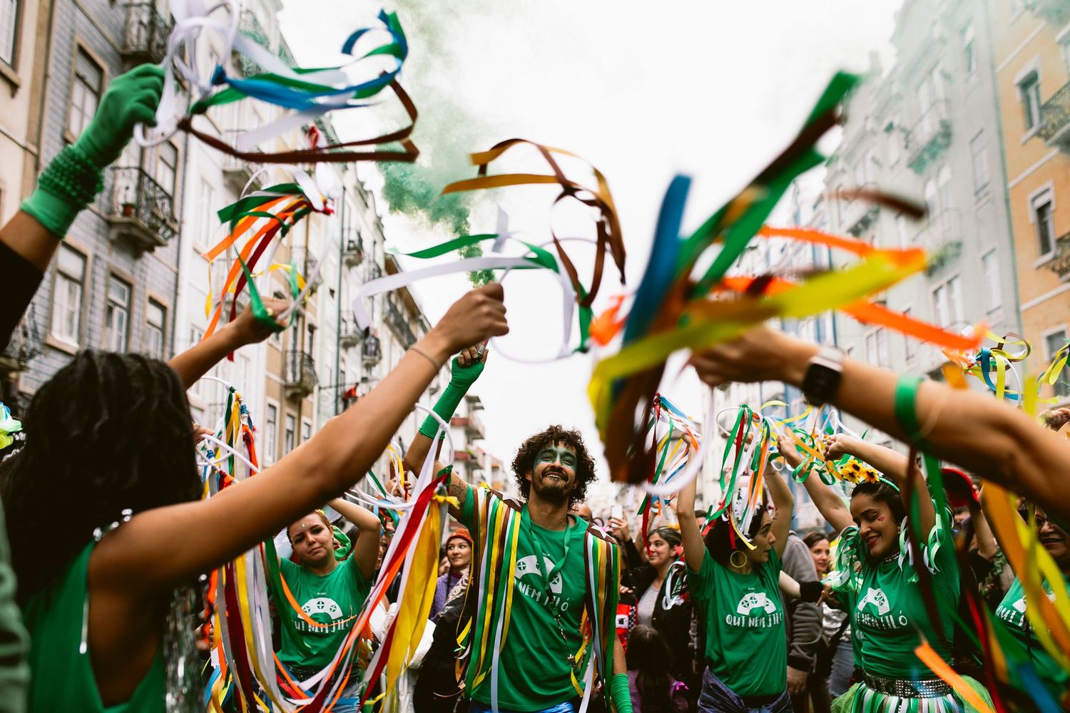 A crowd of sports fans in green jerseys celebrate with raised arms and colorful streamers at a stadium event.