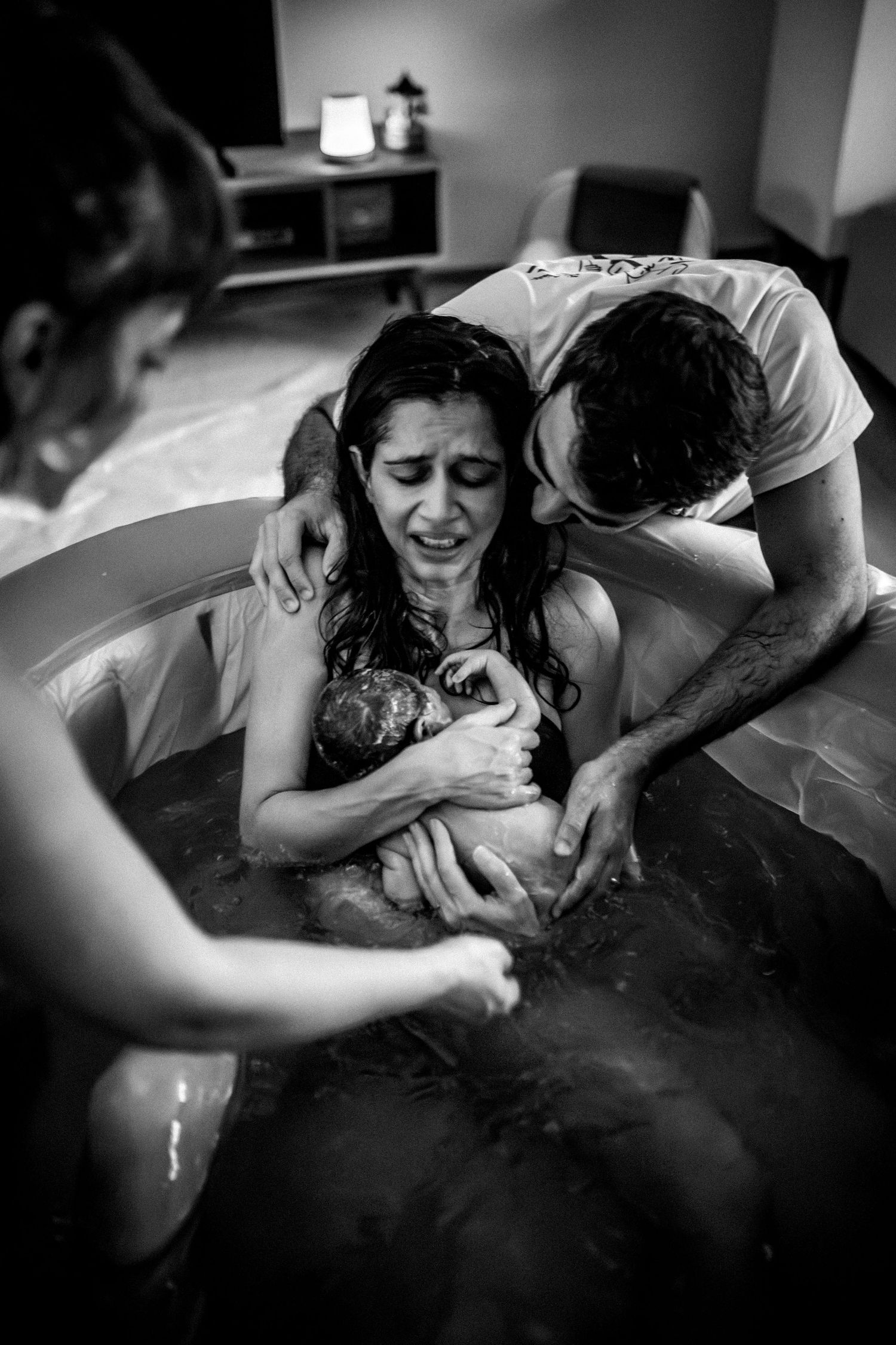 Intimate black and white photography capturing an emotional water birth scene.
