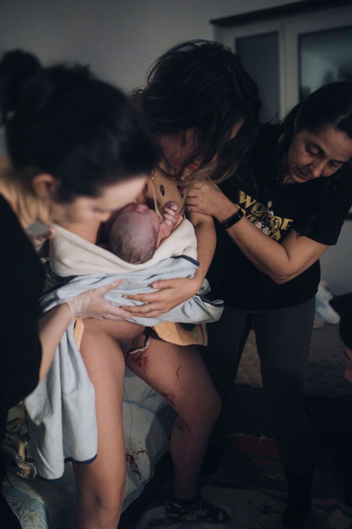 A series of black and white photos showing intimate moments during childbirth in a dimly lit room.