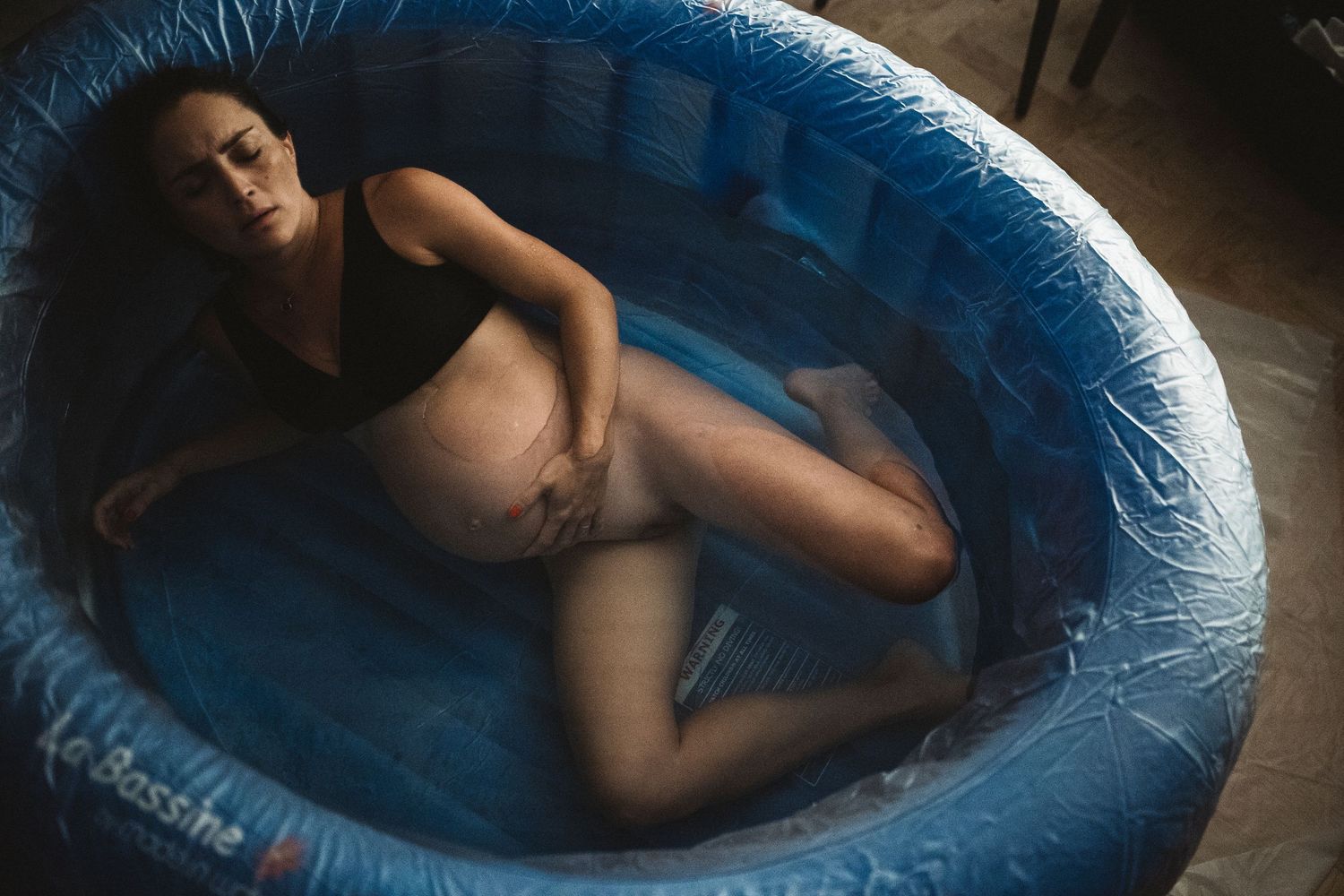 A series of photos showing a figure reclining in a large blue inflatable pool in dim lighting.