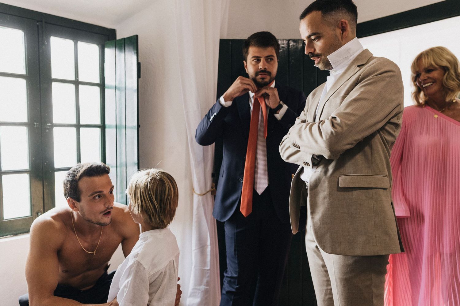 Wedding guests gather indoors near windows during a celebratory moment at a reception.
