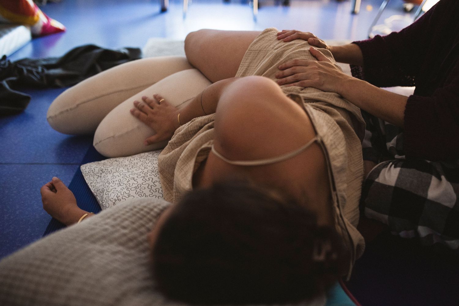 A person lying down and resting on a blue yoga mat during a fitness or relaxation session.