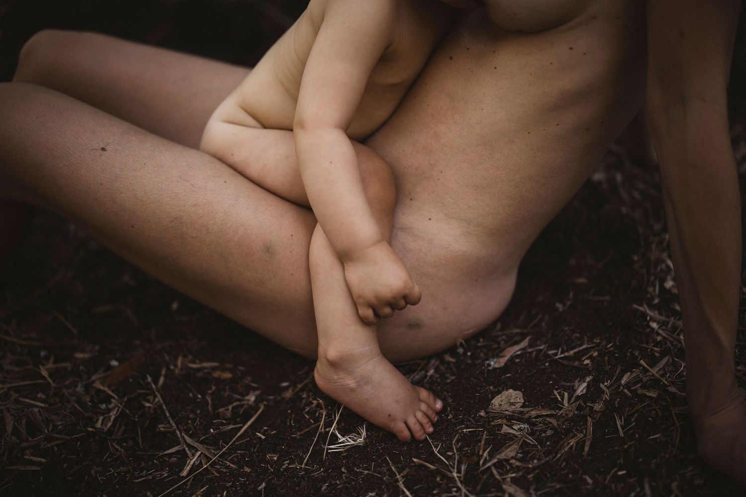 Natural light portrait showing nurturing embrace between parent and young child outdoors.
