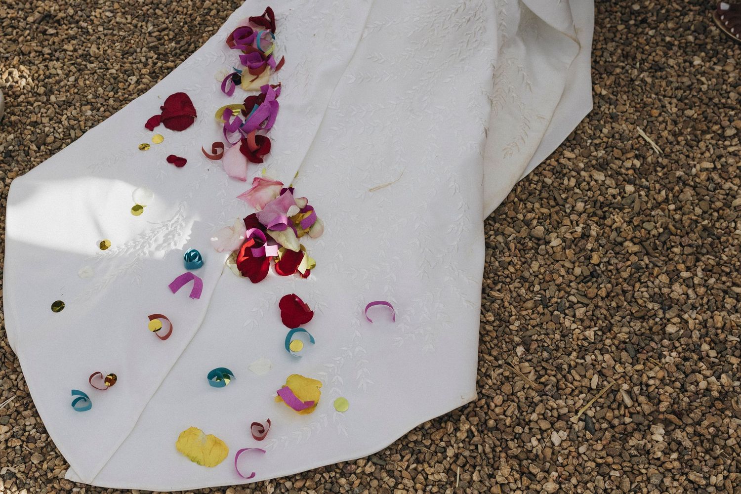 Rose petals scattered on white fabric against a dark brown surface.