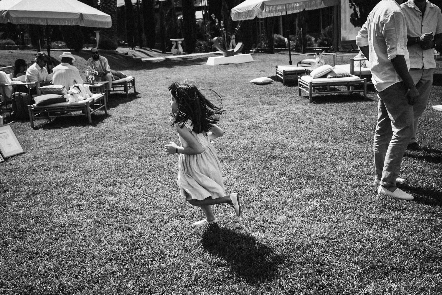Black and white photograph of people playing outdoor games at a summer gathering with cars in background.