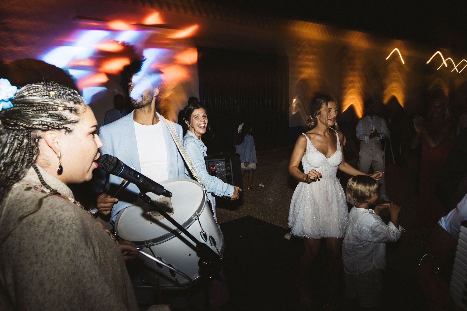 Nighttime wedding reception with colorful lighting and dancing guests.