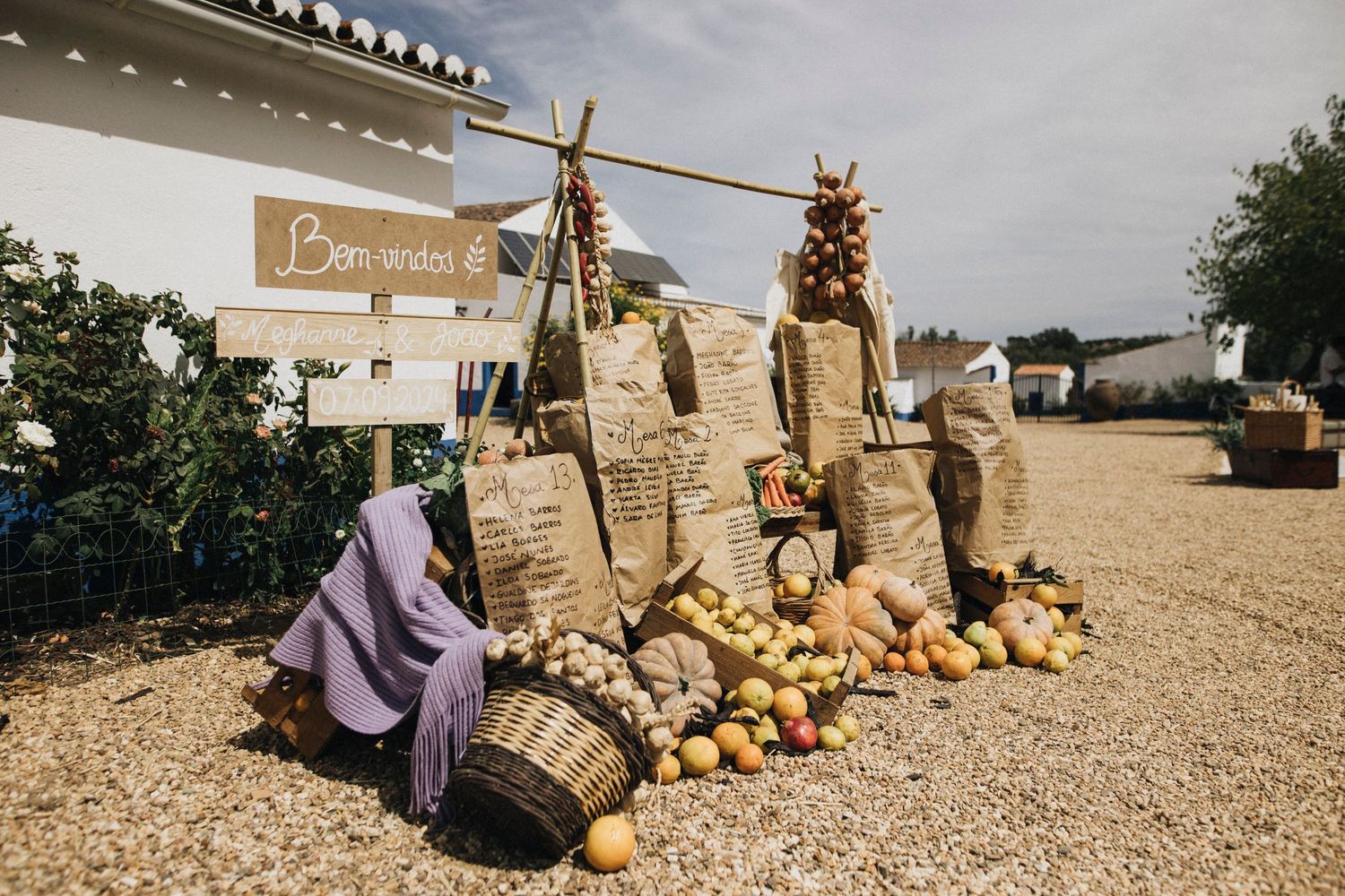 Rustic outdoor wedding venue with straw bales and pumpkin decorations arranged along a gravel path.