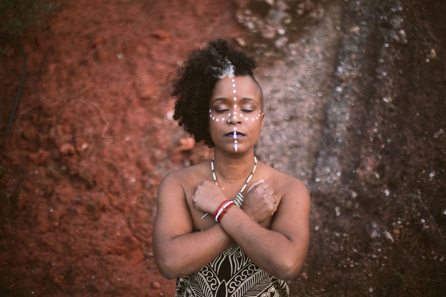 Artistic portrait series with warm red-toned rock wall background.