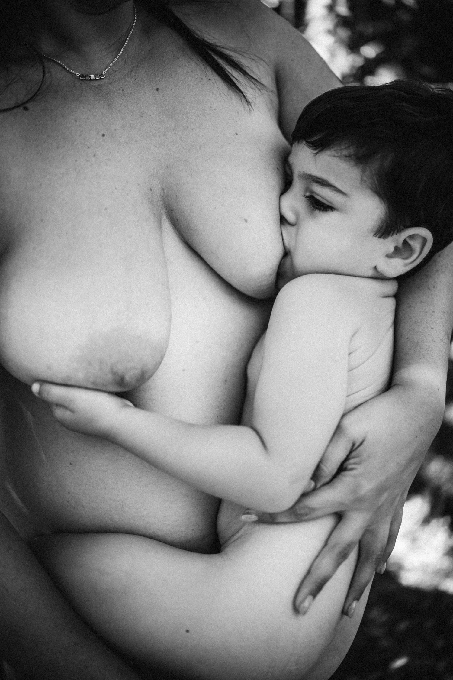 Intimate black and white photography showing close connection during nursing session.