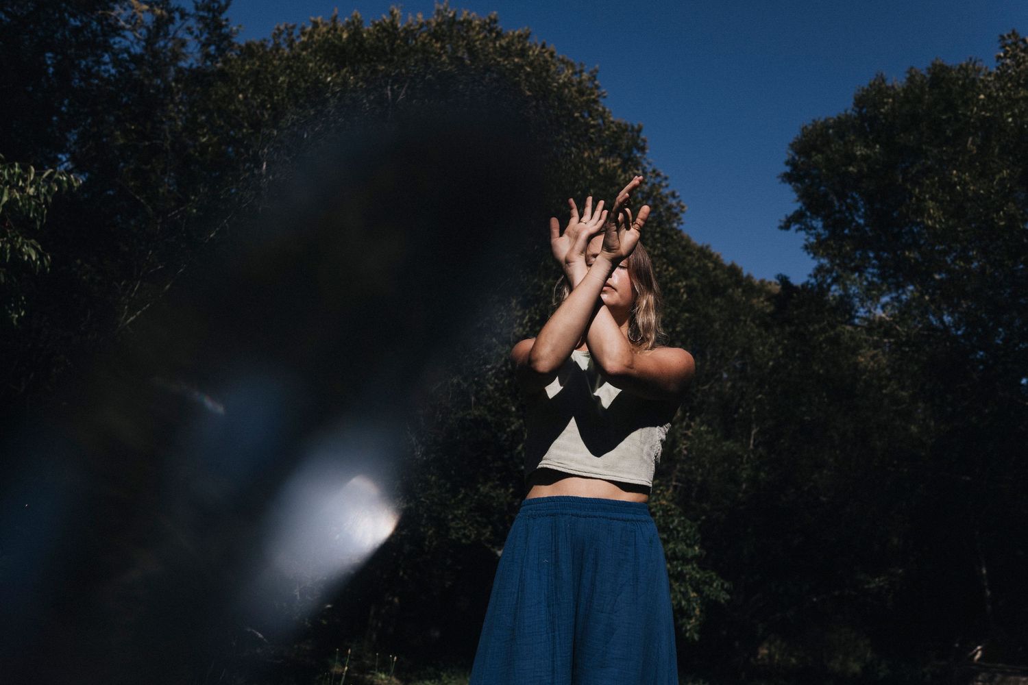 Dramatic outdoor photoshoot against deep blue sky with natural lighting effects.
