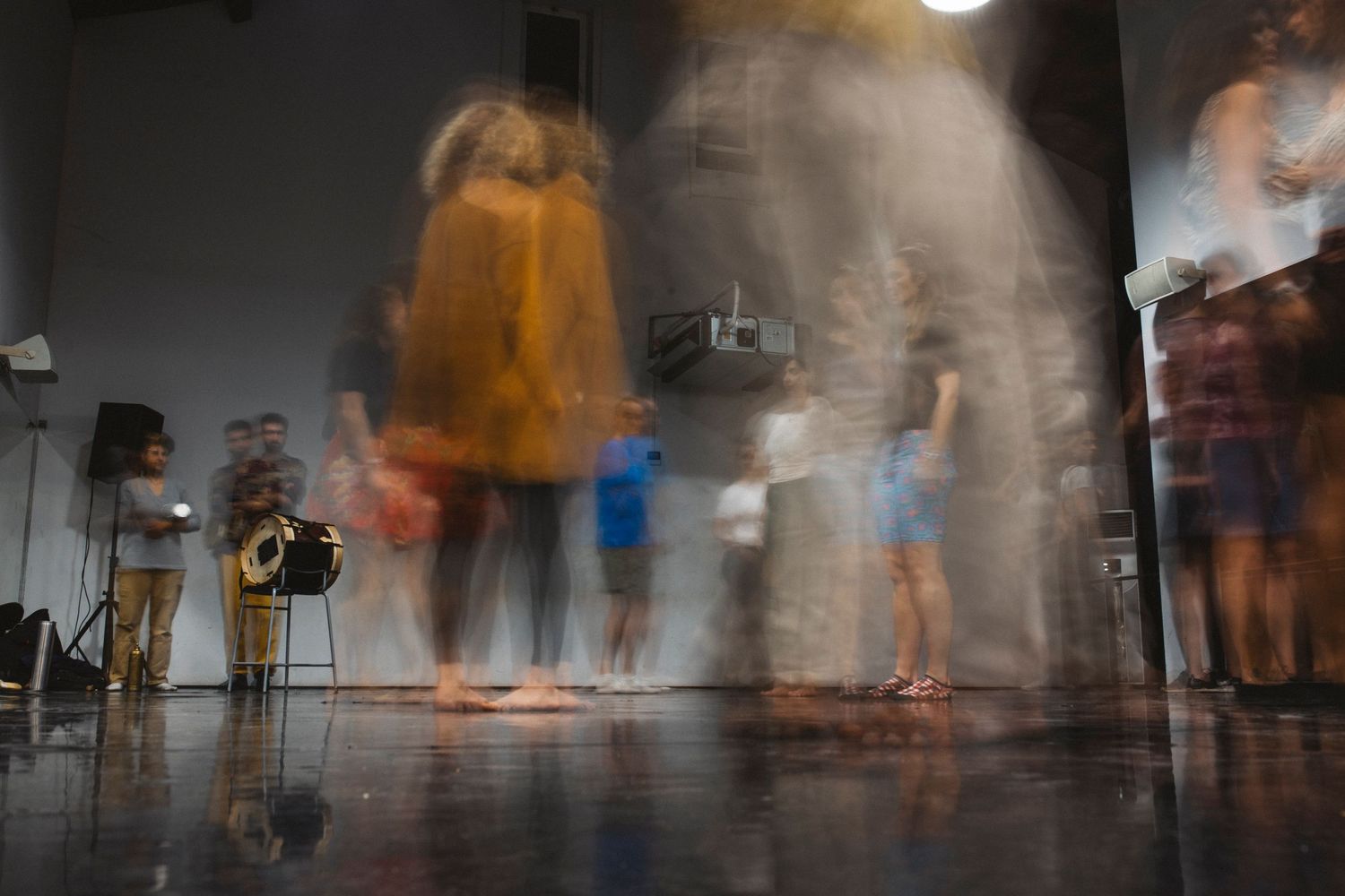 Motion blurred figures move through a dimly lit gallery space creating an ethereal atmosphere.