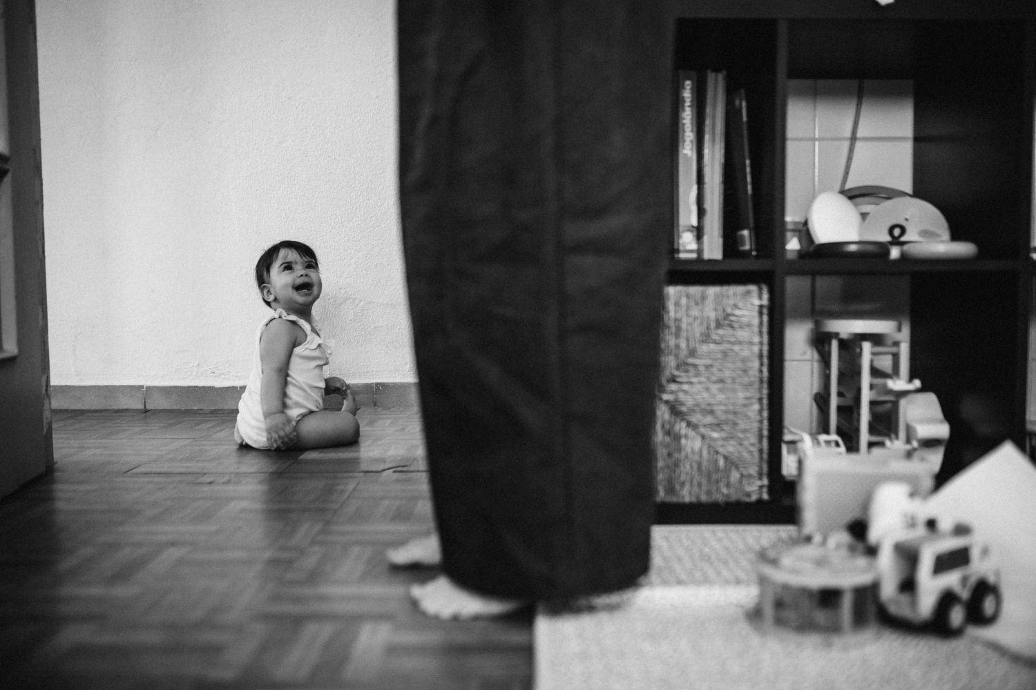 A person's feet and legs are shown walking across a wooden floor in a black and white photograph.