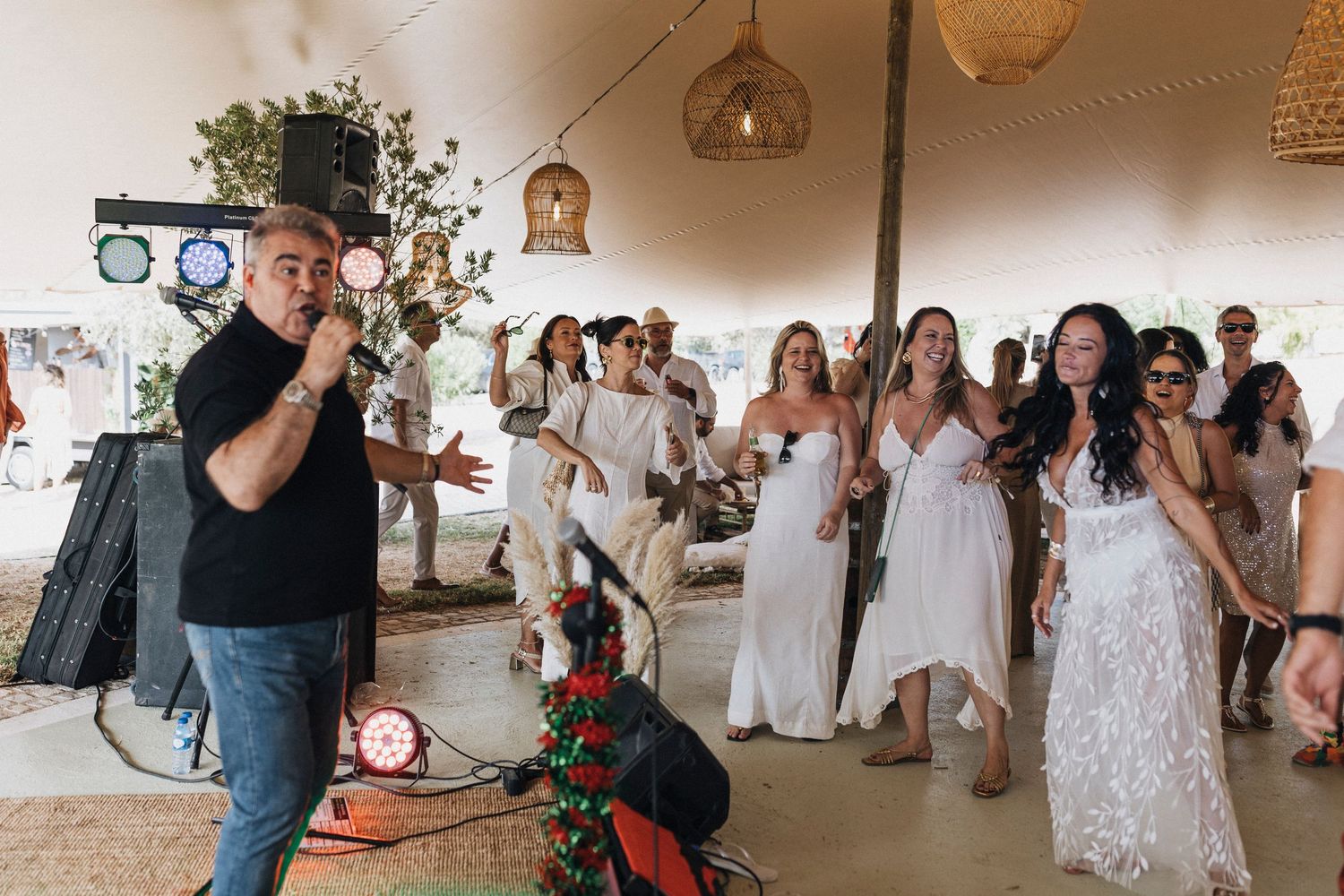 Wedding reception celebration with guests dancing and mingling under white tents during a joyful outdoor party.