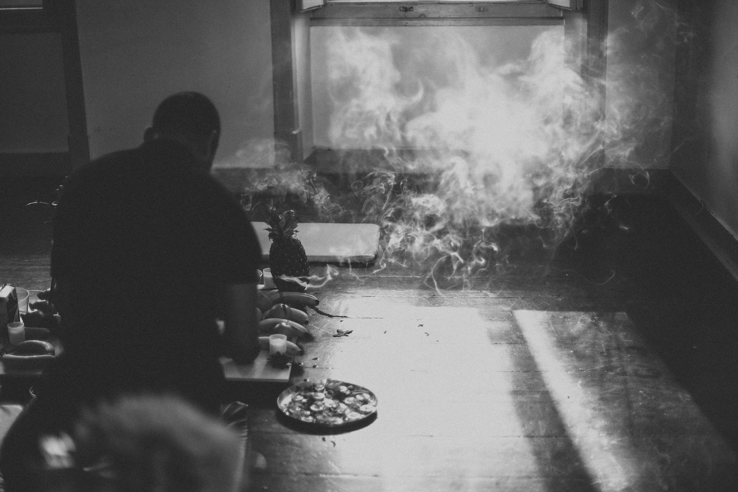 Atmospheric black and white scene with smoke or mist in an indoor setting.