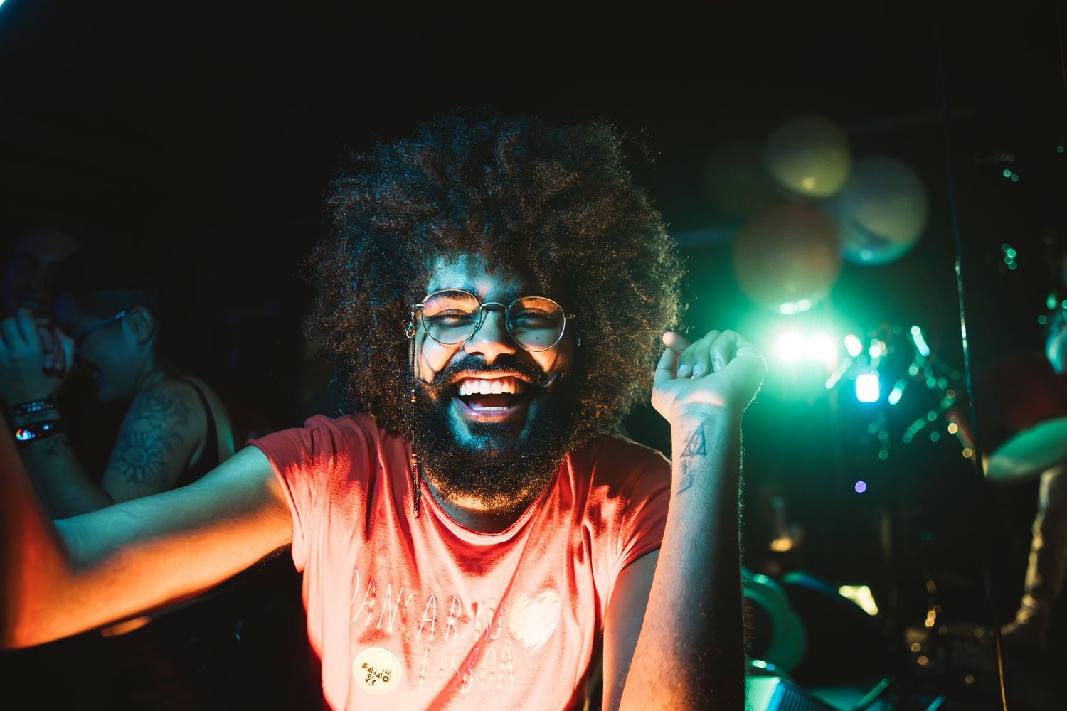 A performer sings passionately on stage under dramatic green and blue lighting at a nightclub venue.