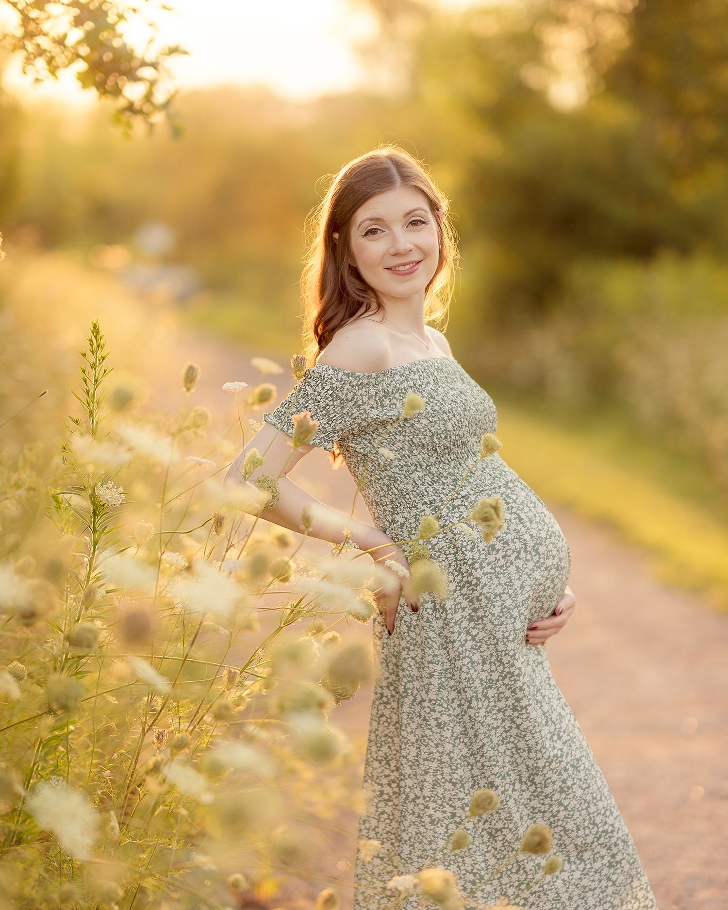 A child in a floral dress twirls joyfully on a sunlit path during golden hour.
