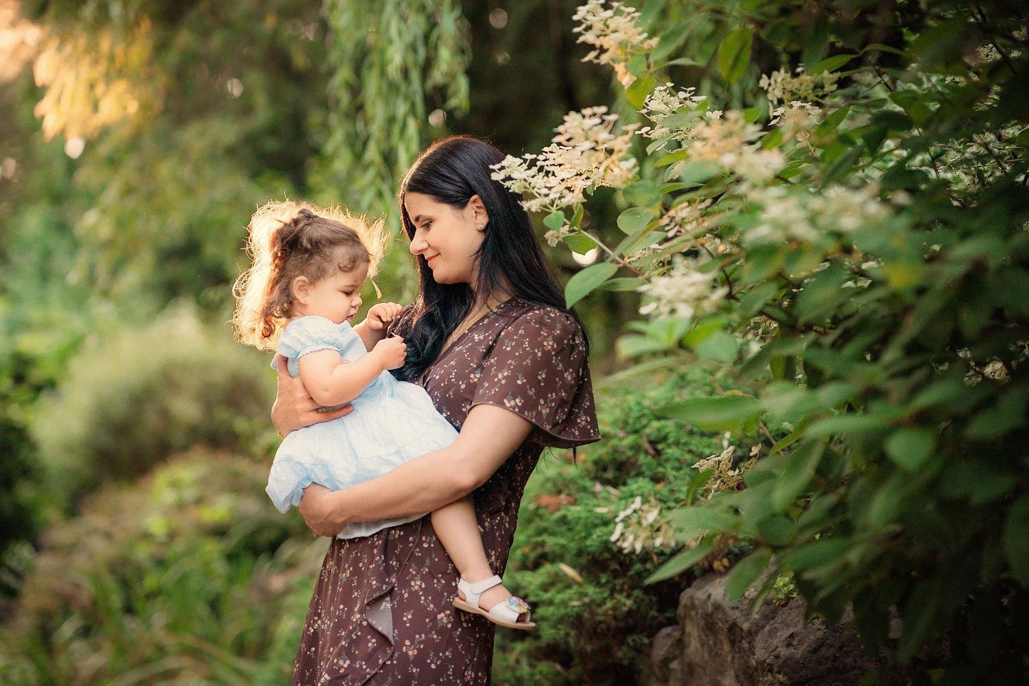 A tender moment shared between parent and child in a lush green forest setting during golden hour.