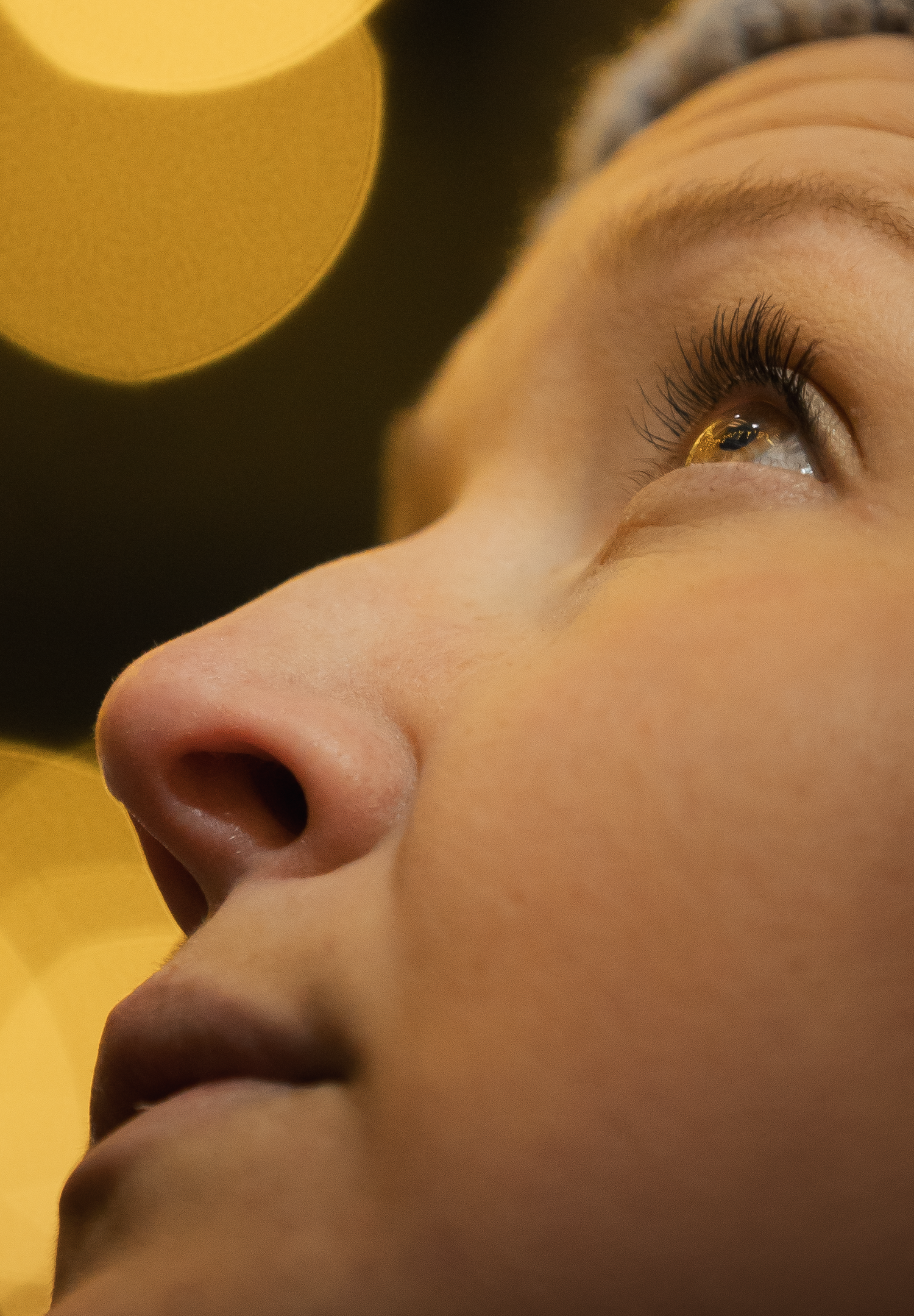 An artistic close-up profile captures long eyelashes against glowing golden orbs.