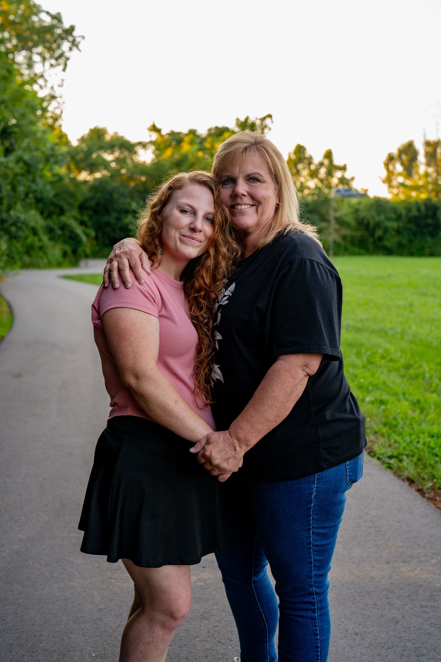 A mother and daughter smiling together during an outdoor portrait session at sunset.