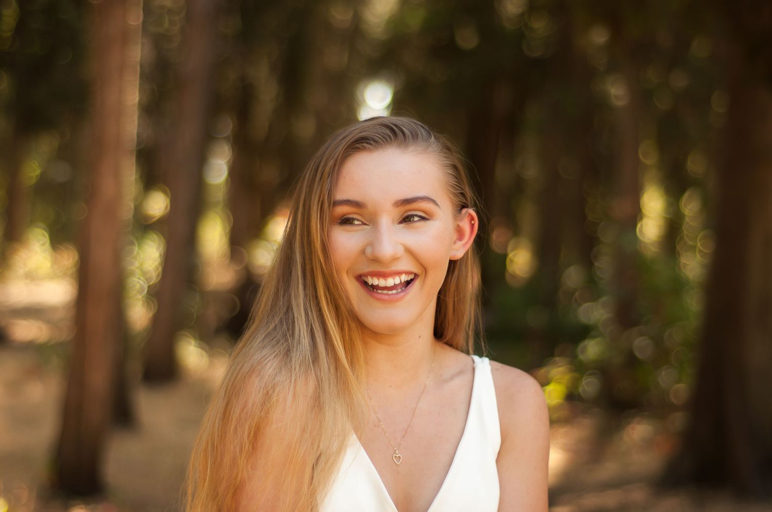 Young woman smiling during a softly lit outdoor portrait session.