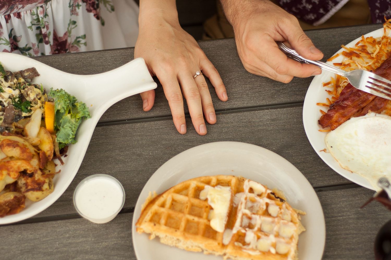 A couple's hands showing engagement ring at a table during a brunch date.