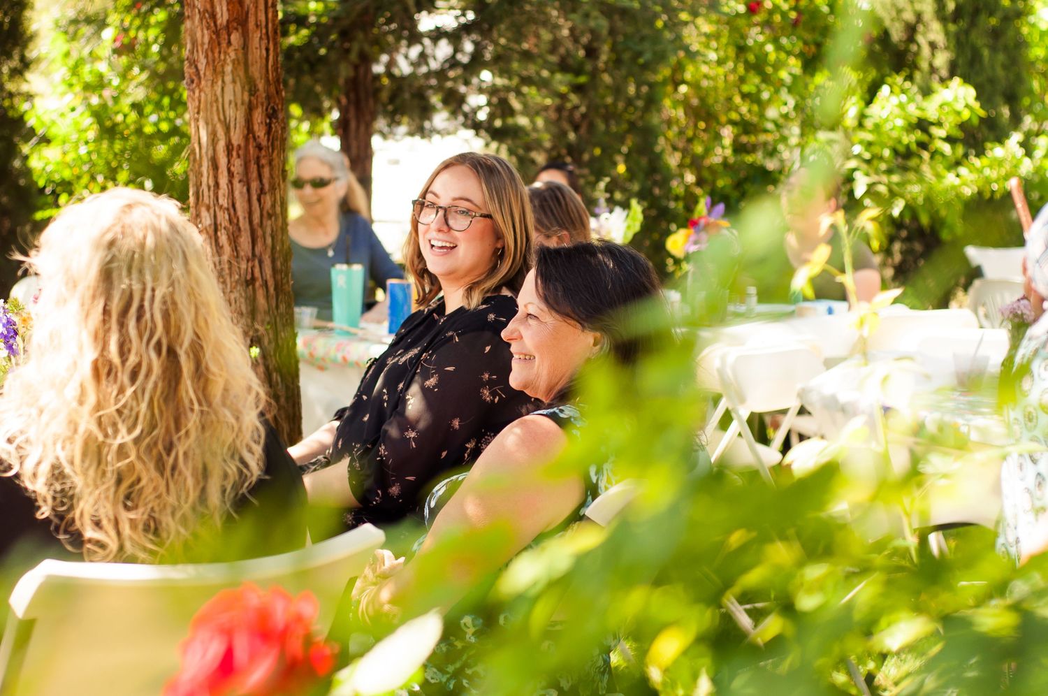 Guests laughing and talking together during a sunny outdoor gathering.