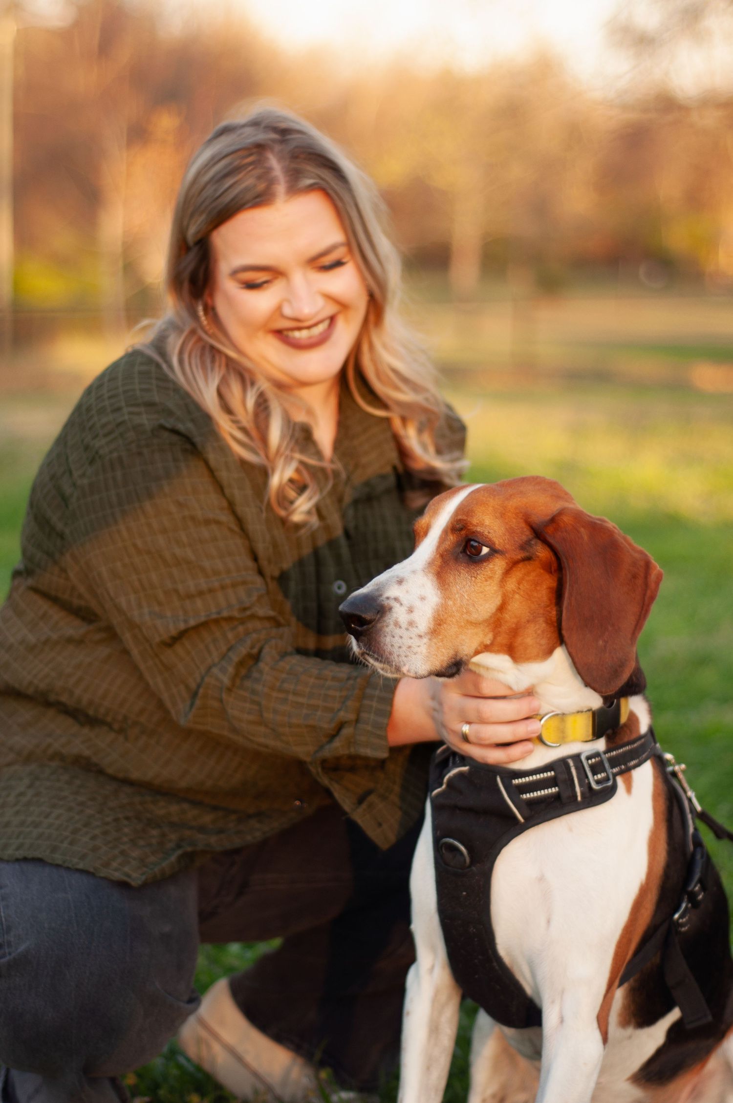 Woman smiling with her dog during a warm outdoor portrait session.