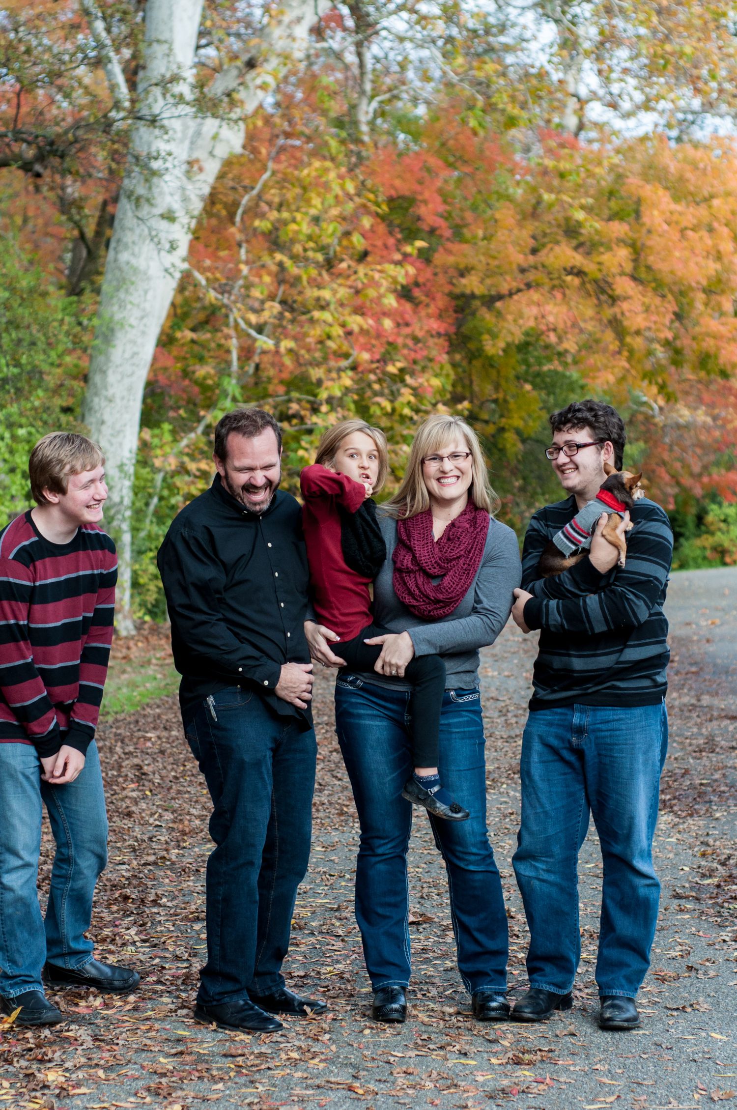 Family standing together among colorful autumn trees during an outdoor portrait session.