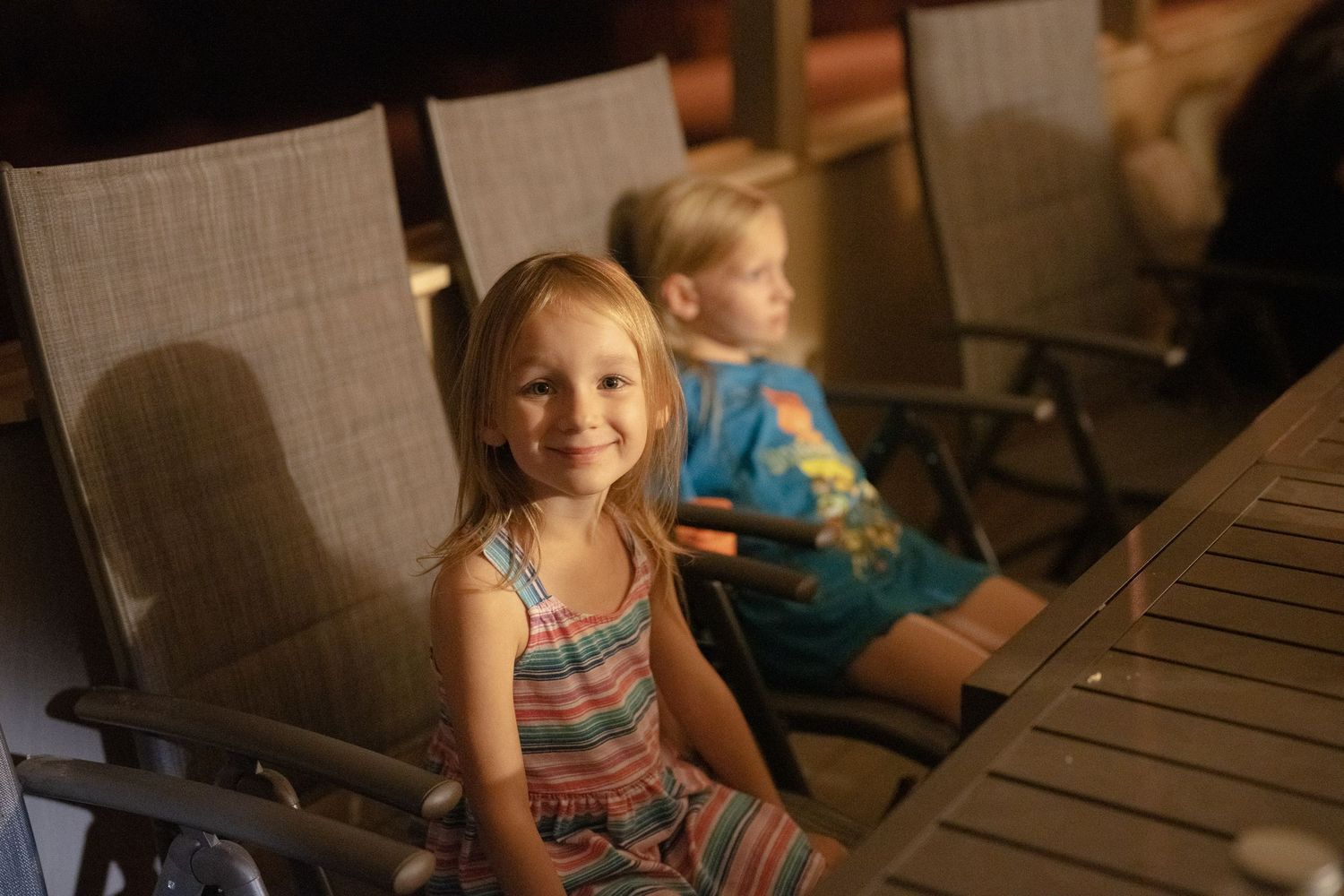 Two young children smiling together at an evening gathering.