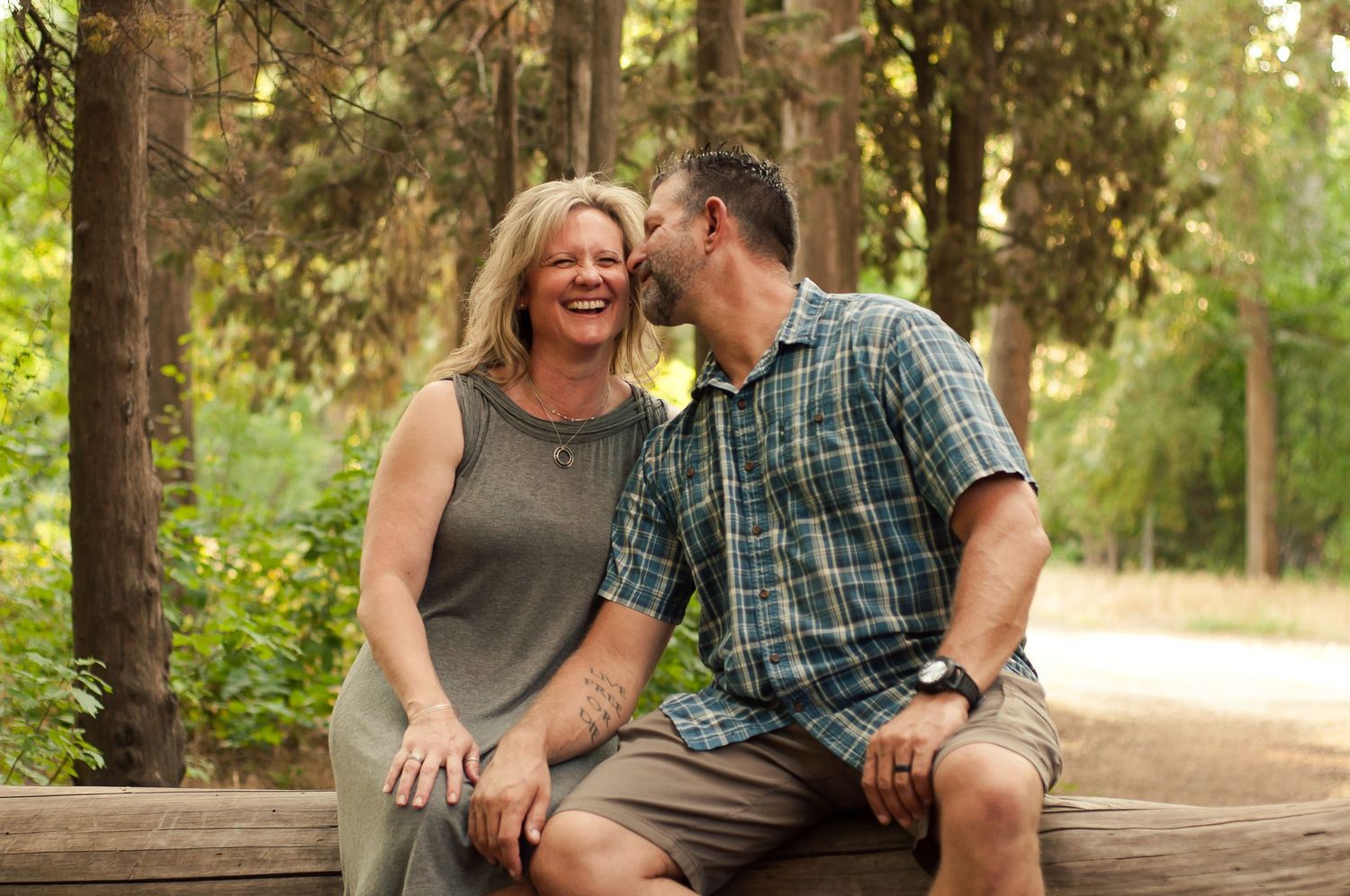 Couple laughing together while seated outdoors during a relaxed portrait session.