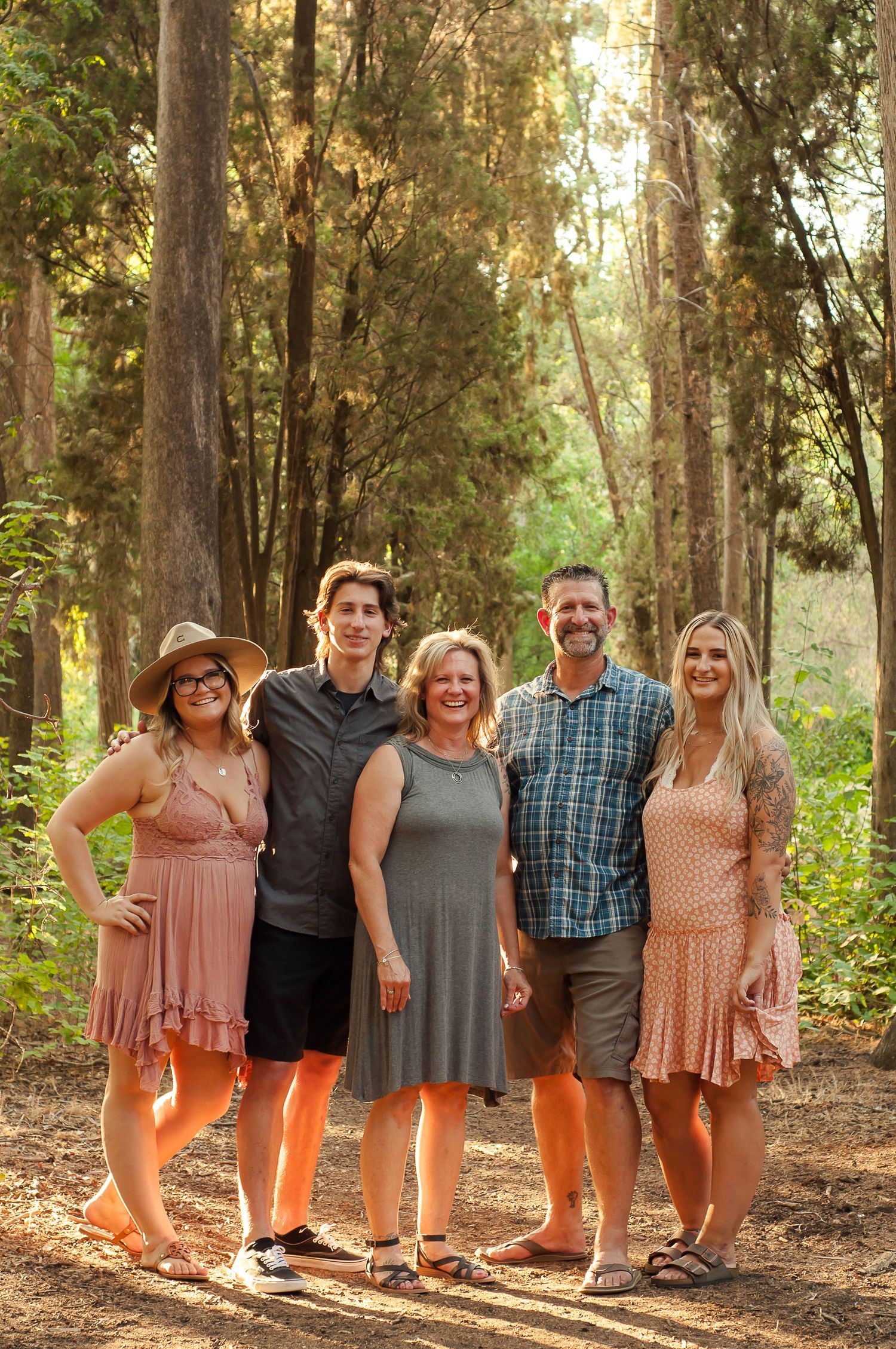 Family standing together among tall trees during an outdoor portrait session.