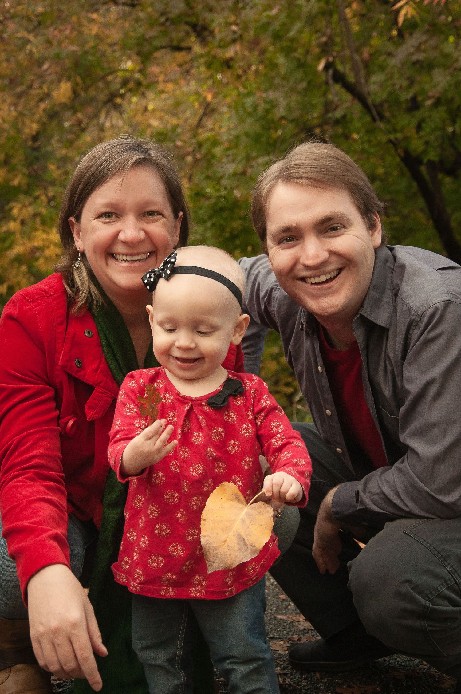 Family of three smiling together during an outdoor fall portrait session.