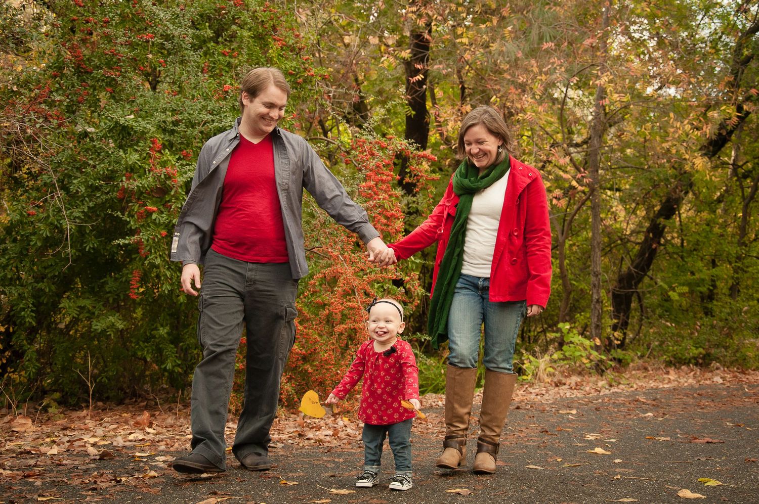 Parents walking hand in hand with their young child during a fall family portrait session.