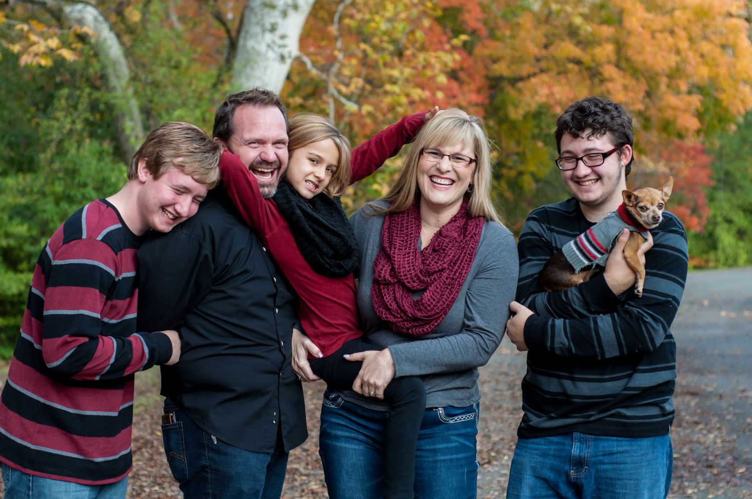 Family laughing together during a playful fall portrait session.