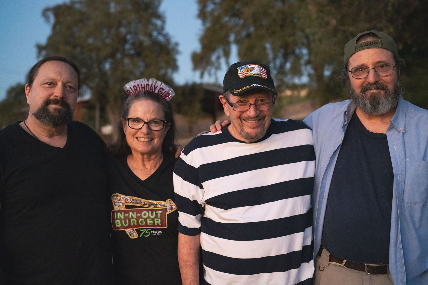 Four adults smiling together during a casual outdoor gathering.