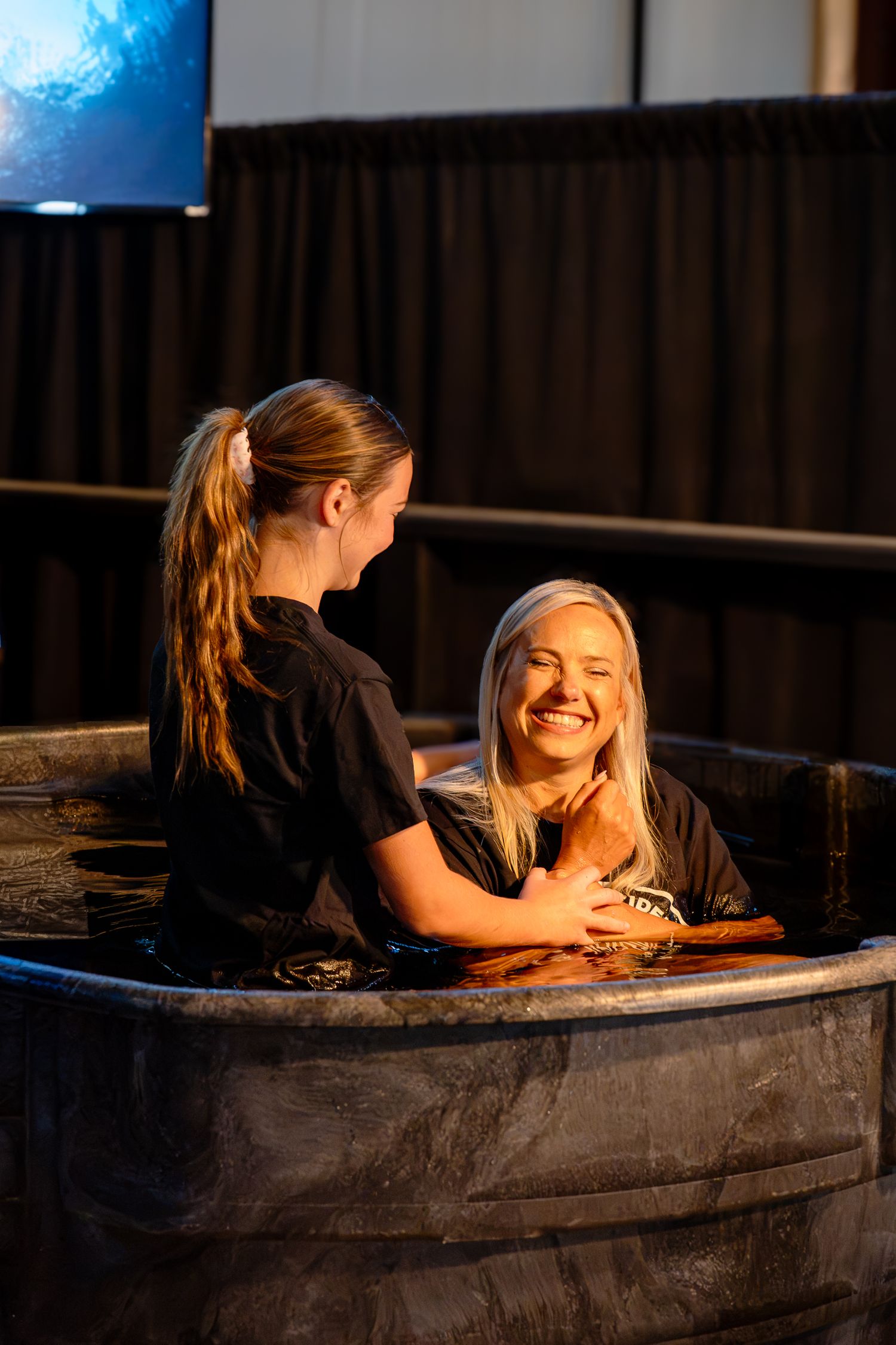 Young woman preparing to baptize another woman during a church service.