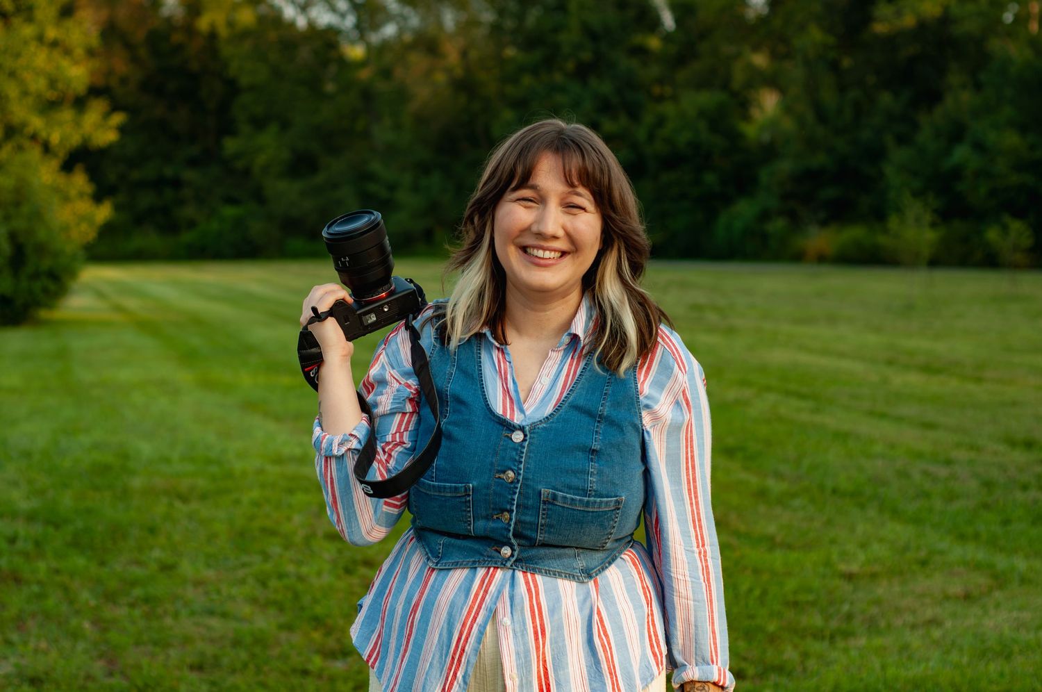 Marie Murray holding her camera during a professional outdoor portrait session at sunset.